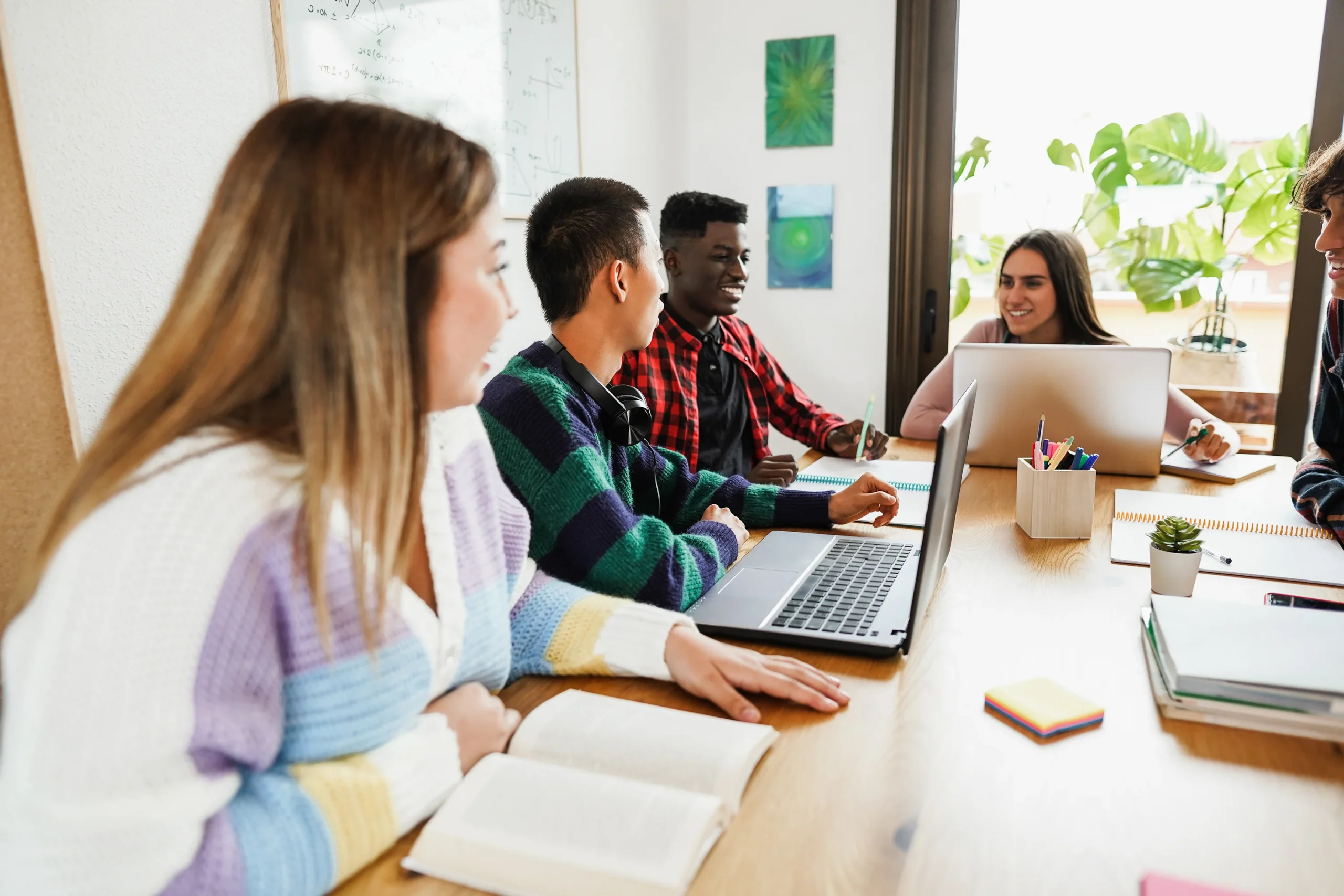 Des élèves multiraciaux lisant des livres et utilisant des ordinateurs portables pendant leurs études à la bibliothèque de l'école