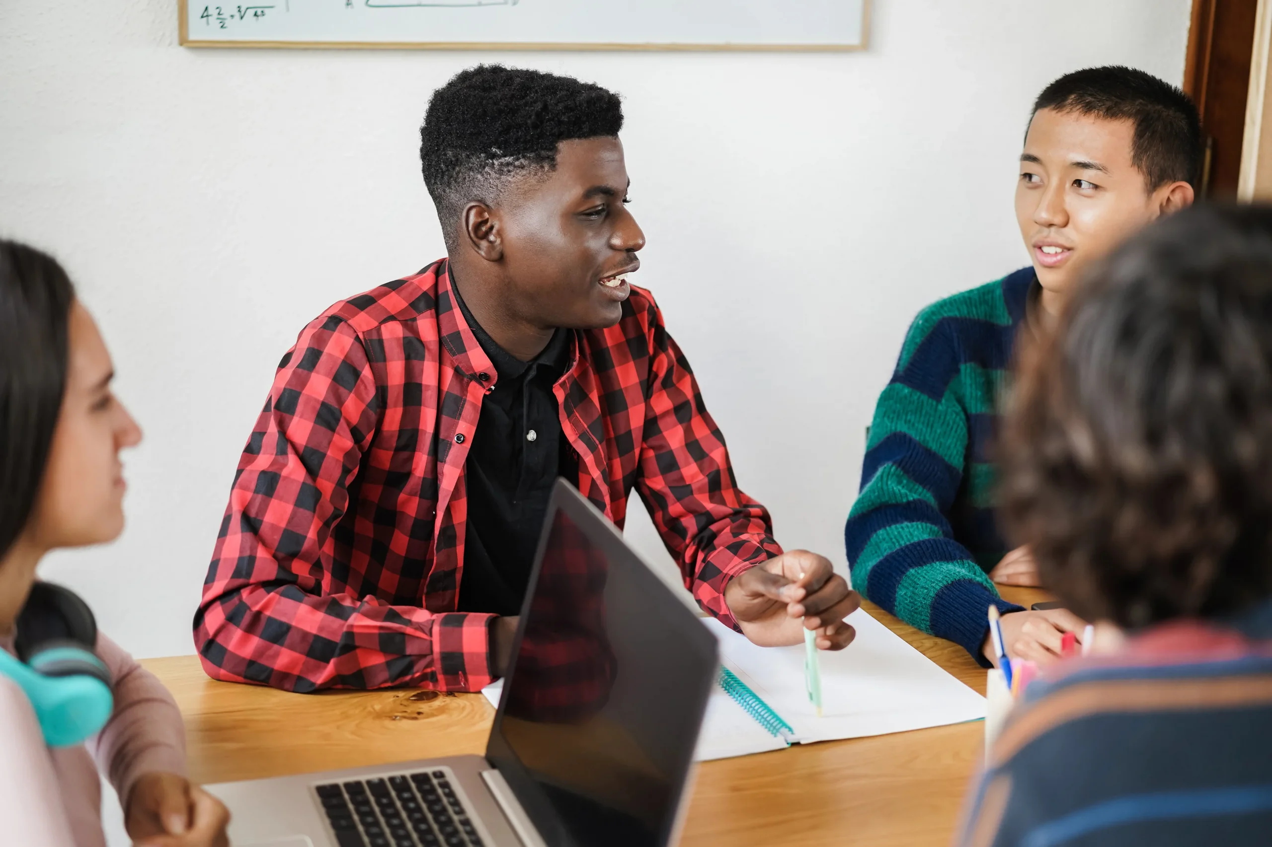 Étudiants multiraciaux utilisant un ordinateur portable pour la recherche de projets tout en étudiant ensemble à l'école